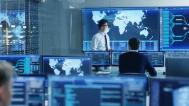 Sistem kontrol odasında Yöneticisi bir brifing onun personeli için tutar. Onlar veri merkezinde iş ve birden çok ekran gösteren haritalar tarafından lojistik veri çevrilidir.