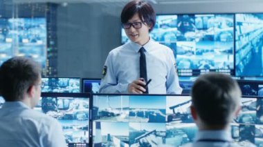 Güvenlik kontrol odasında Şef gözetim memuru bir brifing iki astlarının kişilik tutan. Birden fazla ekranları göstermek o onlar koruma nesne büyük önemi.