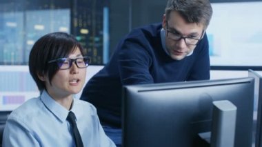 Veri madenciliği merkezinde Şef istatistikçi onun iş istasyonu çevrili monitör verileri görüntüleme ve grafikleri ile onun genç asistanı oturur danışır..
