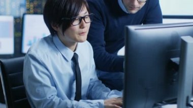 Veri madenciliği merkezinde Şef istatistikçi onun iş istasyonu çevrili monitör verileri görüntüleme ve grafikleri ile onun genç asistanı oturur danışır..