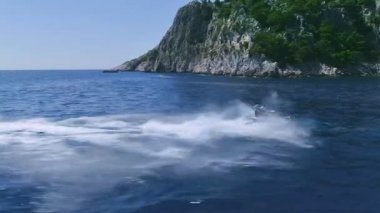 Bir çift yan görünüm içinde belgili tanımlık geçmiş güzel yeşil tepeler ile sürüş dalgalar üzerinde atlama kayak Jet ardından hava.