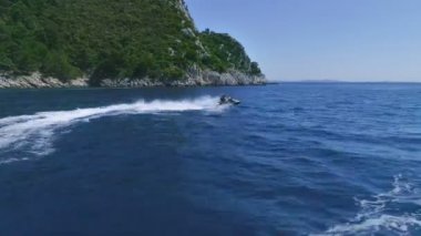 Bir çift yan görünüm çevrelerde sürüş bir Kayak jet ardından hava. İçinde belgili tanımlık geçmiş güzel yeşil tepeler.