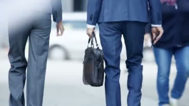 后视图的男性和女性商人走下繁忙的大城市街道 他们都穿着时尚的灰色 蓝色剪裁西装 男人拿着一个袋子 他们匆匆向投资者会议 — 图库视频影像