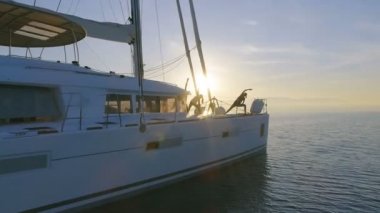 Hava atış üç güzel uygun kadınların bir beyaz yelkenli katamaran tekne sabah Yoga yapıyor. Rising Sun ile huzurlu deniz.