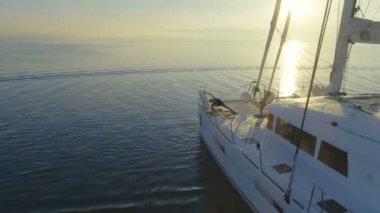 Hava atış üç güzel uygun kadınların bir beyaz yelkenli katamaran tekne sabah Yoga yapıyor. Rising Sun ile huzurlu deniz.