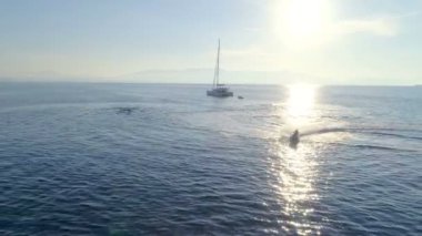 Beyaz yelkenli katamaran tekne ve Jet Ski tarafından çevrelerde sürüş hava görünümünü. Sakin ayna gibi deniz ve güzel bir gün güzel hava.