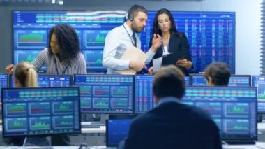 Tüccarlar çok etnik gruptan oluşan takım meşgul Menkul Kıymetler Borsası ofisinde çalışıyor. Bayi ve Broker satın almak ve satmak hisse senetleri piyasasında. Monitörler ilgili Infographics, veri ve sayıların görüntüsünü.