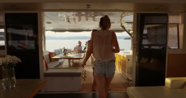 Başarılı gençlerin grup diğerleri kokteyller ile yat Stern katılın. Arka plan sakin deniz ve adalar.