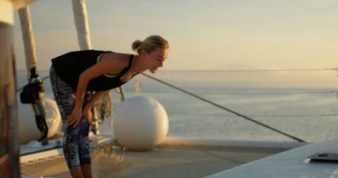 Yakın çekim Shot Yelkenli Yat üzerinde Yoga yaparken zinde bir genç kadın. Arka plan güzel sakin deniz ve açık güneşli gökyüzü.