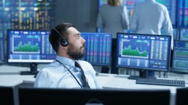 Menkul Kıymetler Borsası tüccar kulaklýklý mikrofon üzerinde büyük müşteri ile bir anlaşma yapar. O diğer brokerleri ile çalışıyor ve Surround bilgisayar grafik ve Ticker numaraları ekranlarında.