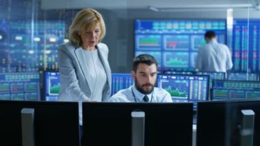 Hisse senedi piyasasında profesyonel yatırımcı ile firma Bölüm Başkanı konuşuyor. Ekranlar ile çizge ve Ticker sayý çevrili konum.