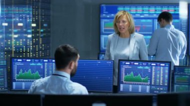 Satış / Alış bölümü kadın Yöneticisi görüşmeler erkek tüccar ile borsada. Çalışma arka plan insanlarda ekranlarını göster Ticker numaraları ve grafikler.