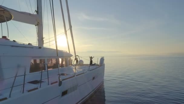 空中拍摄的三美丽适合妇女做早操在白色帆船双体船 太阳升起的和平海洋 — 图库视频影像