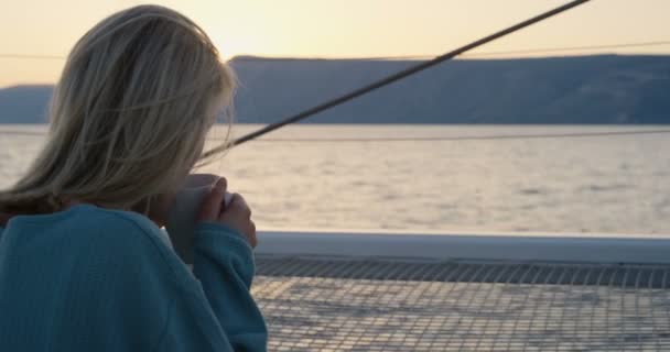 美丽的年轻女性饮料热饮料在游艇甲板上和钦佩日落 — 图库视频影像
