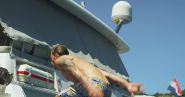 スローモーション撮影運動若い男が海にヨットのスイムプラット フォームからバク転をします — ストック動画