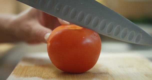 一个人的特写镜头切西红柿在一个木板上的锋利的刀 — 图库视频影像