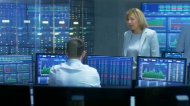 Satış / Alış bölümü kadın Yöneticisi görüşmeler erkek tüccar ile borsada. Çalışma arka plan insanlarda ekranlarını göster Ticker numaraları ve grafikler.