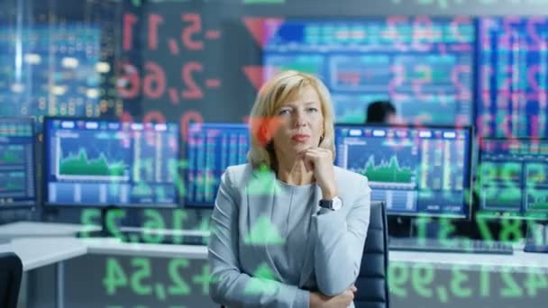 股市女高层经理查看预计的股票代号和图表 在她的房间后面满是屏幕和统计数据 — 图库视频影像
