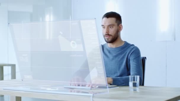 在不久的将来 坐在他的工作站上的人在他的现代电脑上用透明的显示器工作 显示使用交互式图表和图形显示用户界面 — 图库视频影像