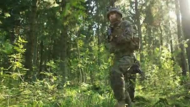 小队五名装备精良的士兵进行侦察军事任务 他们正通过茂密的森林进入编队 低角度跟随镜头 — 图库视频影像