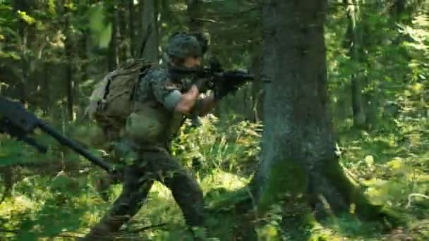 アクションの軍事作戦は つの分隊小銃射撃位置に敵の攻撃迷彩ユニフォームを着て兵士の整った 彼らは 鬱蒼とした森を介して形成で実行しています 側面ビュー ロング ショット — ストック動画