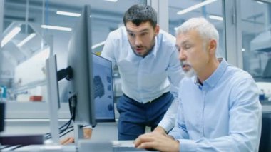Endüstriyel tasarımcı konuşma Kıdemli mühendis ile yeni bileşen tasarımı Cad programında çalışırken vardır. O inşaat üstünde kişisel bilgisayar ile iki monitör.
