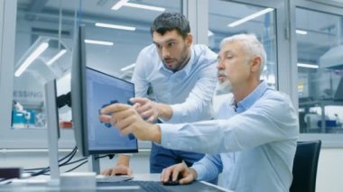 Endüstriyel tasarımcı ürün tartışma Kıdemli mühendis ile yeni bileşen tasarımı Cad programında çalışırken vardır. O inşaat üstünde kişisel bilgisayar ile iki monitör.
