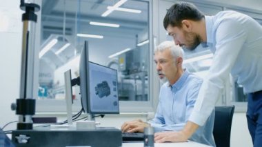 Endüstriyel tasarımcı tartışma Kıdemli mühendis ile yeni bileşen tasarımı Cad programında çalışırken vardır. O inşaat üstünde kişisel bilgisayar ile iki monitör.