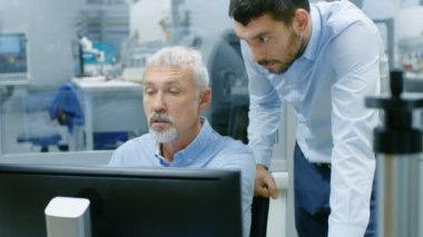 Proje Yöneticisi ve Kıdemli mühendis var proje ilgili konuşma kişisel bilgisayarda çalışırken. Ofis pencere elektronik imalat fabrikası dışında görünür olduğunu.