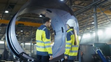 Erkek sanayi işçisi kask erkek şef mühendis metal işleme fabrikası'nın yeni projesi tartışıyorlar. Onlar ağır sanayi tesisi ortasında Stand.