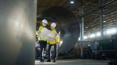 Erkek ve dişi Endüstri mühendisleri proje planları Surround boru hattı parçaları büyük ağır sanayi fabrikası üretim ortasında tarafından ayakta iken bak