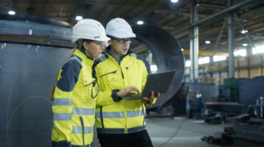 Erkek ve kadın Endüstri mühendisleri da zor şapka tartışmak yeni proje kullanarak Laptop süre. Onlar ağır sanayi Gestures.They çalışmaları gösteren fabrika üretim yapmak. Ufak bir olasılık.