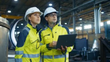 Erkek ve kadın Endüstri mühendisleri da zor şapka tartışmak yeni proje kullanarak Laptop süre. Onlar ağır sanayi Gestures.They çalışmaları gösteren fabrika üretim yapmak. Ufak bir olasılık.