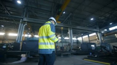 Erkek ve kadın Endüstri mühendisleri da zor şapka tartışmak yeni proje kullanarak Laptop süre. Ağır metal bileşenleri etrafında yalan ile fabrika üretim sektöründe çalışırlar. 360 arc View çekim.