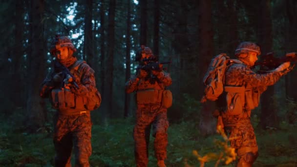 小队五名装备精良的士兵伪装在侦察军事夜任务 它们被红色耀斑点燃 穿过茂密的森林 — 图库视频影像