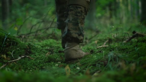 特写装备精良士兵的靴子踩在苔藓上 人在茂密的森林中进一步移动 他在侦察军事任务低角度素材 — 图库视频影像