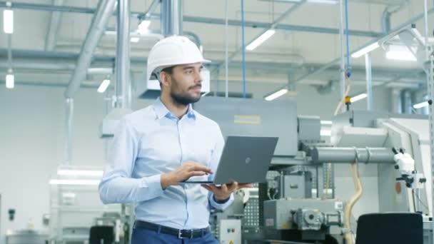 硬帽带着笔记本电脑穿行轻便现代工厂的总工程师 在现代工业环境中成功 英俊的男人 — 图库视频影像