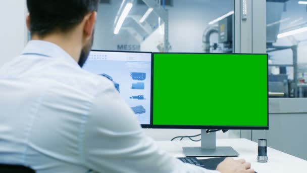 工程师在一台个人电脑上使用绿色屏幕模拟屏幕 他正在设计 Cad 程序中的新组件 出办公室窗口组件制造工厂可见 — 图库视频影像
