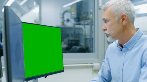 Seior 工业工程师在一台个人电脑上使用绿色屏幕模拟屏幕 他正在设计 Cad 程序中的新组件 出办公室窗口组件制造工厂可见 — 图库视频影像