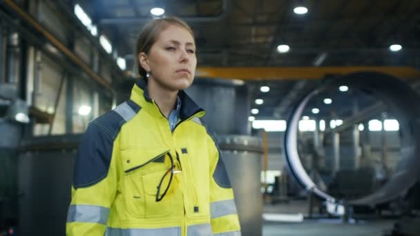 女工在重工工厂行走时戴上保护安全帽 在背景下 可以看到各种金属制品部件 — 图库视频影像