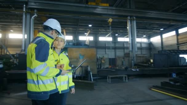男性とハード帽子議論の新しいプロジェクトでラップトップを使用している間 女性産業エンジニア 彼らは転がって金工コンポーネント工場重工業で働きます アーク ビュー ショット — ストック動画