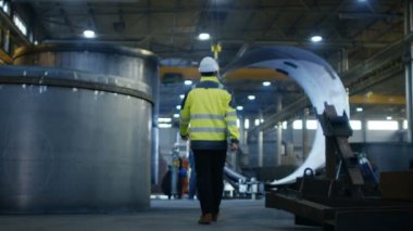 Ağır fabrika çeşitli metal işleme süreçleri ile imalat sanayi endüstri mühendisi sabit hat Emanet ceket arkadan görünüm size yürür.