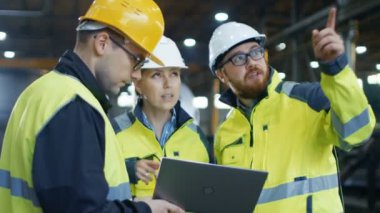 Üç Endüstri mühendisleri fabrika işçisi kullanarak Laptop süre ile konuş. Onlar ağır üretim tesisi sanayi iş.