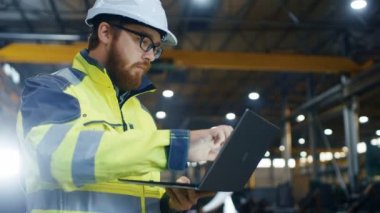 Endüstri Mühendisi sabit hat Emanet ceket dokunmatik ekran Laptop kullanıyor. O ağır fabrika üretim sanayi çalışıyor. Arka plan kaynak içinde / Metal maden işleme işlemleri sürüyor.