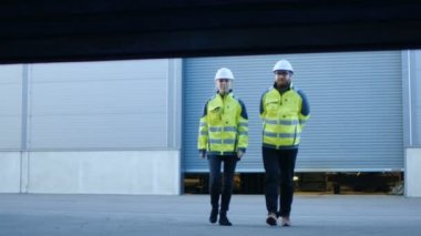 Sert şapkalar ve emanet ceketler giyen erkek ve dişi fabrika işçilerini fabrika açılış kapılar girin.
