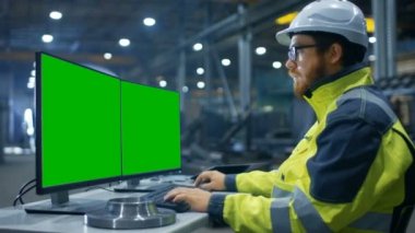 İçinde ağır sanayi fabrikası endüstri mühendisi kişisel bilgisayar ile iki yeşil Mock-up perde üzerinde çalışmaktadır..