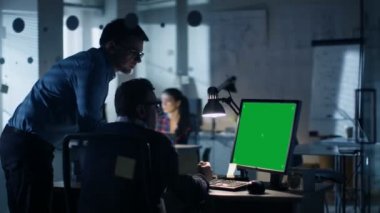 İki Endüstri mühendisleri tartışma var gece geç saatlerde, kişisel bilgisayar izole yeşil ekran Mock-up ekran gösterir. Ofis Modern planları duvarlara dolu görünüyor.
