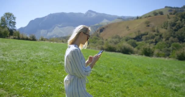 Szép Fiatal Szőke Napszemüveg Használ Mobil Telefon Miközben Réten Dombok — Stock videók