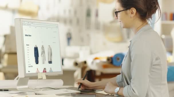女性时尚服装设计师在个人电脑上使用数字绘图片 她设计了新的网上零售商店网站 在背景阳光工作室与织物和缝纫项目 — 图库视频影像
