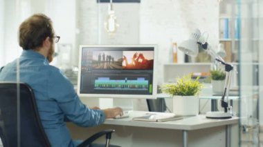 Erkek Video Editor görüntüleri ve ses ile iki göstermek onun kişisel bilgisayarda çalışır. O parlak Office çatı katında çalışıyor.